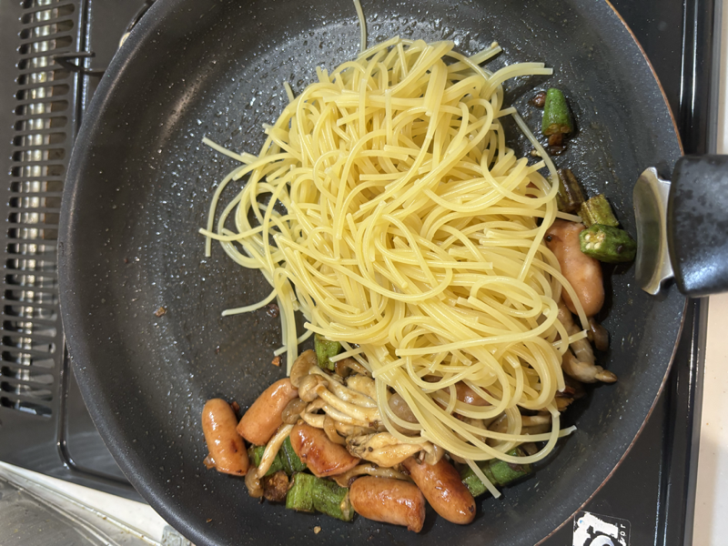 具材の上に茹でたパスタを加えたフライパン