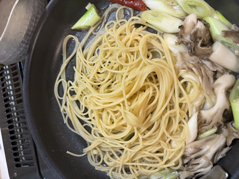 長ネギとまいたけの横に茹でたパスタを加えたフライパン