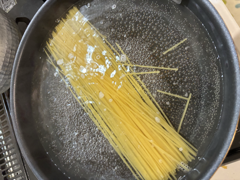 フライパンで茹でているスパゲッティ