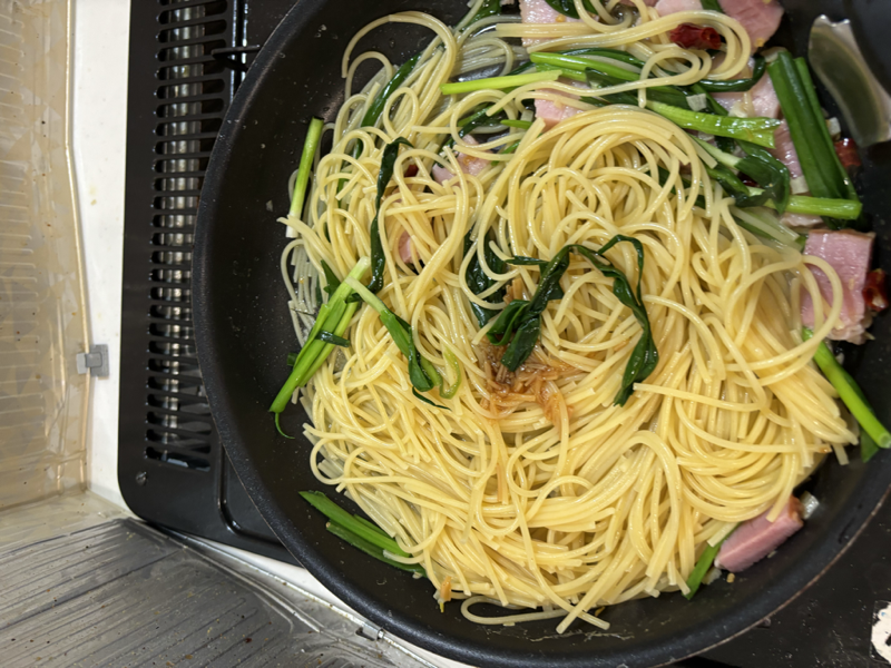 青ネギとベーコンを和えたパスタの中央に七味なめ茸をのせたフライパン